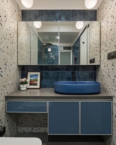 Bathroom vanity with blue oval vessel sink, blue glossy cabinets, terrazzo walls, and mirrored cabinet above.
