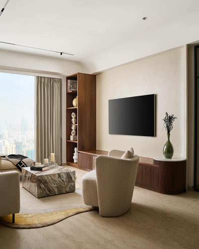 Neutral living room with walnut shelving, mounted TV, boucle armchair and marble coffee table by city-view window