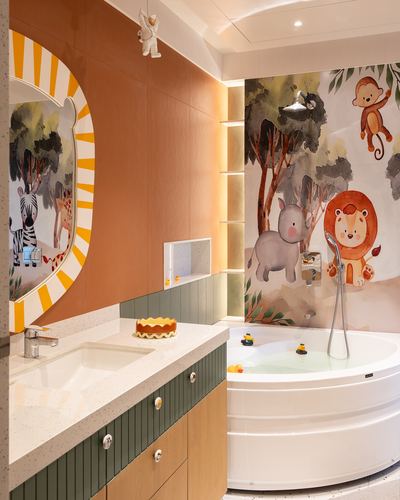 Kids bathroom with jungle mural wall, round tub, sunburst mirror and terrazzo counter