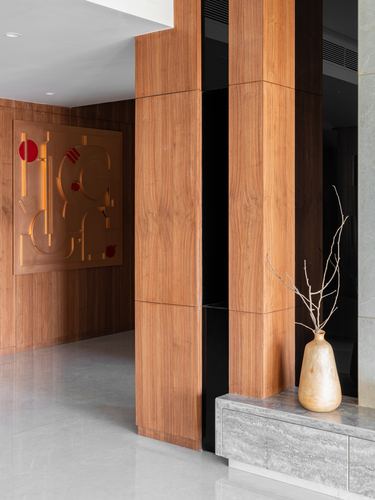 Wood-panelled entryway corner with stone console, ceramic vase and abstract metallic wall art