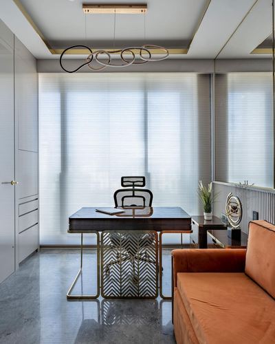 Home office with dark marble desk, mesh chair, orange velvet sofa and sculptural pendant light