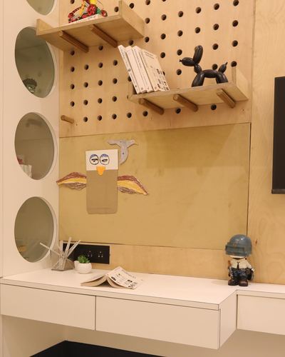 Plywood pegboard wall with wooden shelves, oval mirrors, and a white floating desk in a study nook