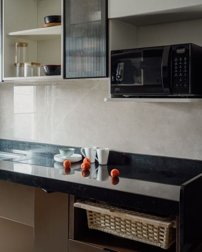 Kitchen counter with black stone top, microwave shelf, and reeded glass cabinet above