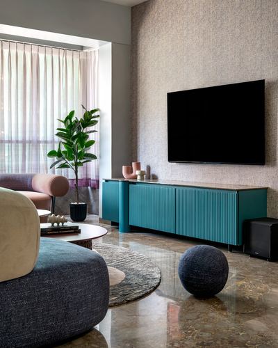 Living room with teal fluted media console, textured wall, marble floor, and pink armchair by window