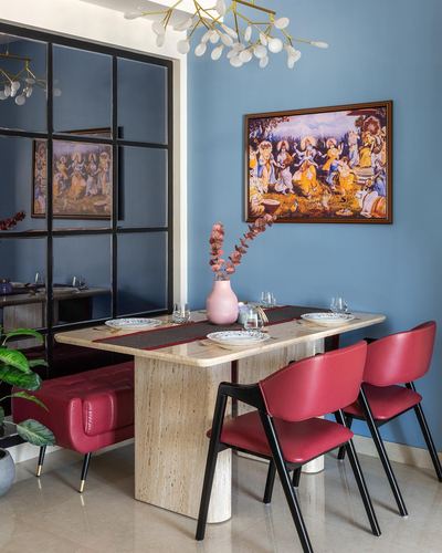 Dining nook with stone table, red leather chairs, blue wall and framed Indian folk painting
