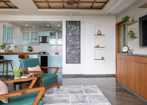 Living room with teal armchairs, kitchen beyond, coffered ceiling and niche wall art