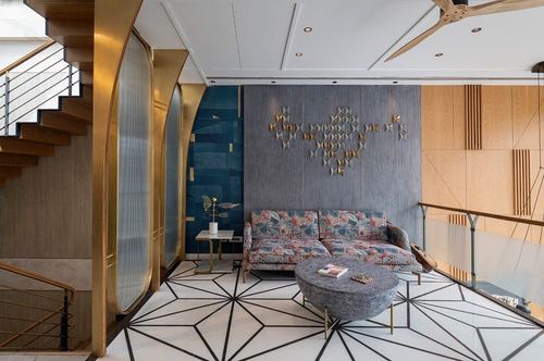 Living room with floral sofa, round textured coffee table, brass-edged partitions, and geometric floor pattern