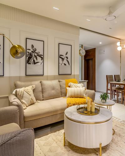 Beige living room with mustard cushions, fluted coffee table, gold floor lamp, framed botanical art