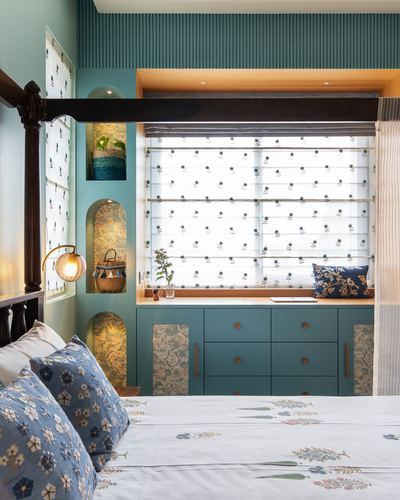 Teal bedroom with carved four-poster bed and built-in floral window seat with arched niches