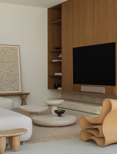 Minimalist living room with wood-panelled TV wall, boucle sofa, sculptural side tables, and a wavy accent chair