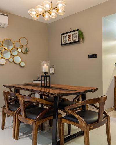 Dining room with live-edge wood table, curved wooden chairs, and cluster of round mirrors on taupe wall