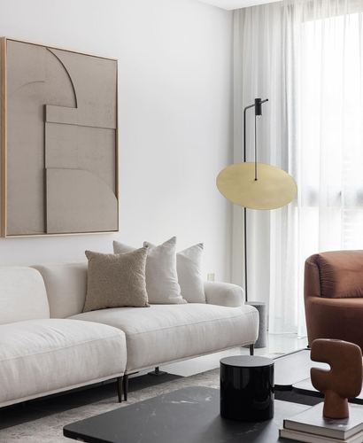 Beige living room with linen sofa, abstract art, brass disc floor lamp, and marble coffee table