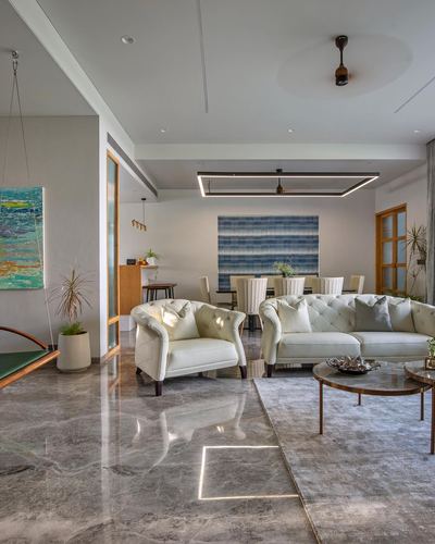 Open living and dining room with cream tufted sofas, marble floor and hanging swing chair