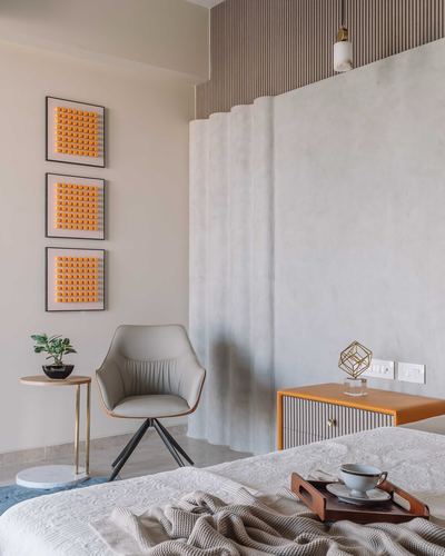 Bedroom corner with grey leather chair, orange fluted nightstand and sculpted plaster wall panel