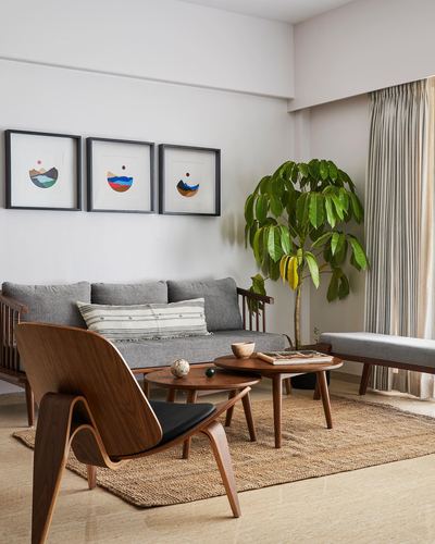 Living room with grey sofa, molded wood chair, nesting tables and framed art triptych