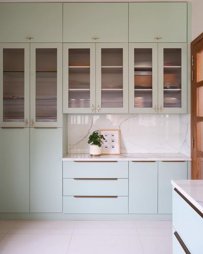 Sage green kitchen cabinetry with fluted glass doors, brass hardware and marble backsplash
