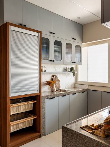 Modern kitchen with grey cabinetry, wooden roller-shutter pantry, fluted glass doors, and granite counters