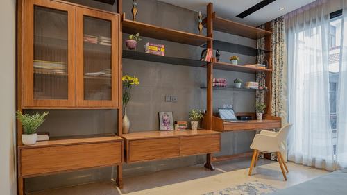 Wooden shelving unit with cabinets, desk and chair against a grey textured wall near a window