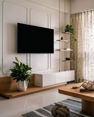 Minimalist living room with wall-mounted TV, wooden console, hanging shelves, and sheer curtains