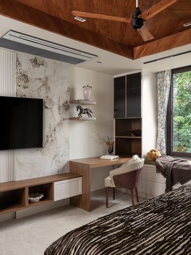 Bedroom corner with stone feature wall, tv, wood ceiling, desk and window seat