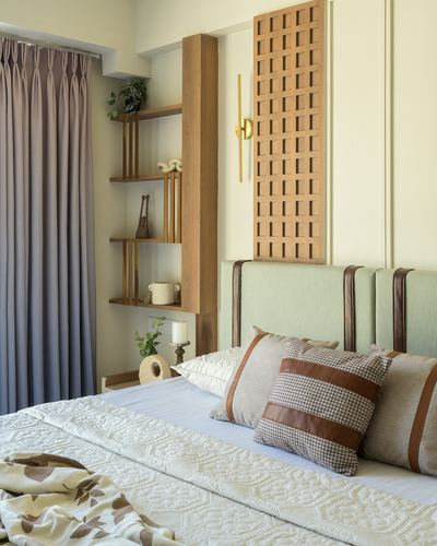 Bedroom with sage upholstered headboard, wood lattice wall panel, and open wood shelving beside mauve curtain