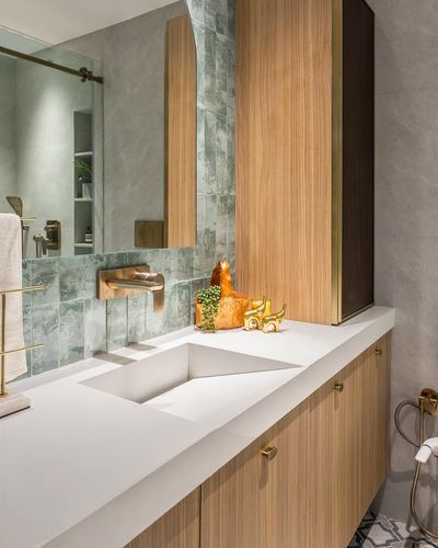 Bathroom vanity with faceted white sink, wood cabinetry, and green textured tile backsplash
