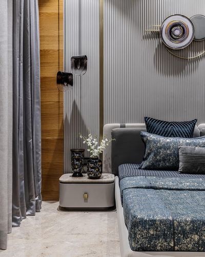 Bedside vignette with fluted grey wall panels, sculptural disc art, and navy textured bedding