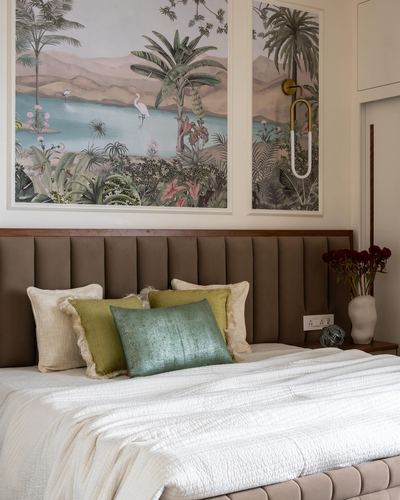 Bed with brown tufted headboard, green and cream pillows, under two framed tropical wildlife murals