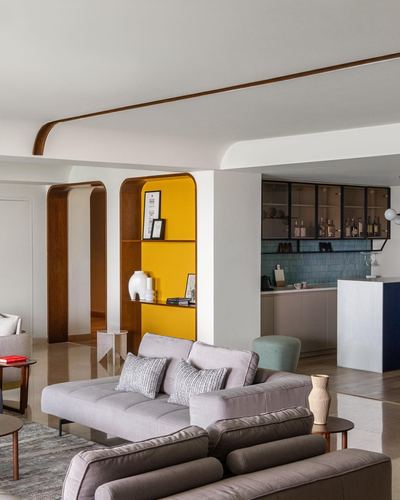 Living room with mustard arched shelf, wood-trimmed arches, and view into blue-tiled kitchen