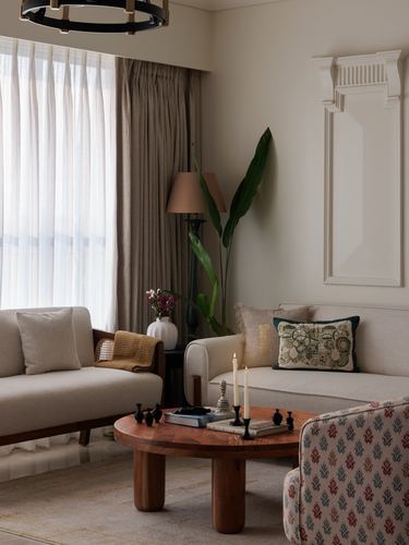 Neutral living room with round wood coffee table, beige sofas, and raised wall panelling