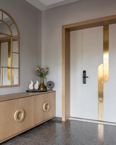 Foyer with arched brass mirror, wood console, and gold-inlaid entry door on terrazzo floor