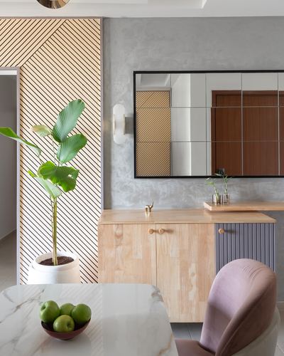 Foyer with diagonal wood-slat wall, mirror, wood console, potted plant and marble table with pink chair