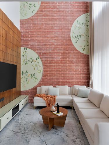 Living room with exposed brick wall, painted circular motifs, cream sectional and marble floor