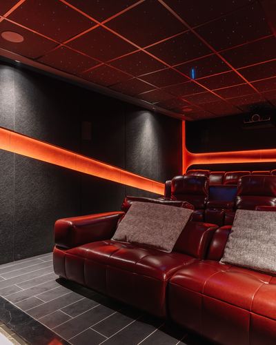 Home theatre with tiered red leather recliners under a starlit ceiling and orange cove lighting