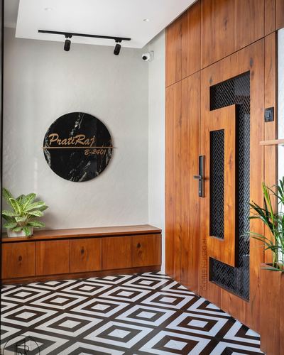 Entrance foyer with wooden door, jali metal insert, circular stone nameplate and geometric floor tile