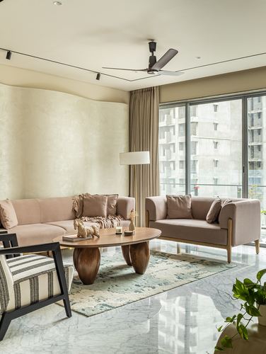 Living room with curved plaster wall, pink sofas, sculptural wood coffee table and city view