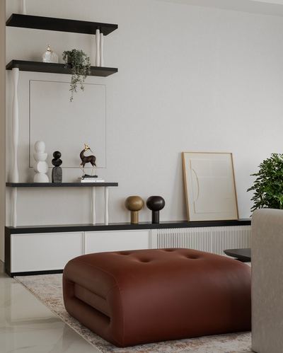 Living room corner with black open shelving, decor objects, and a large rust leather tufted ottoman.