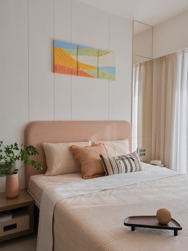 Bedroom with curved pink upholstered headboard, layered pillows, and a woven landscape textile above the bed