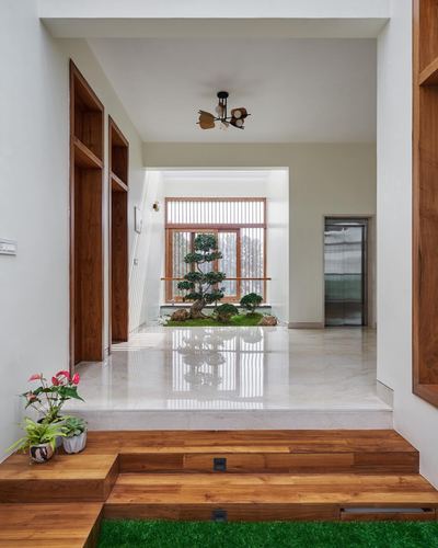 Foyer with wooden steps, marble floor, and indoor garden with bonsai tree centered under a window