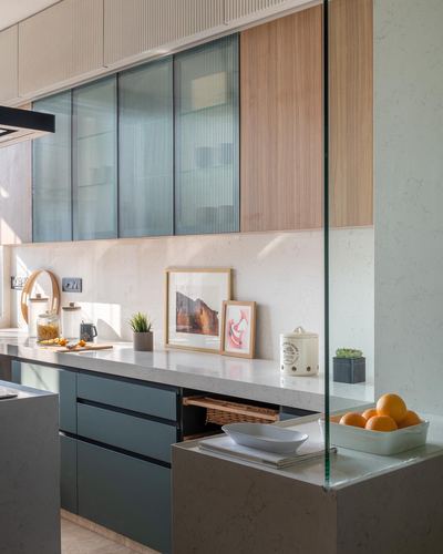 Kitchen counter with framed art, fruit bowl, and fluted glass cabinets in warm daylight