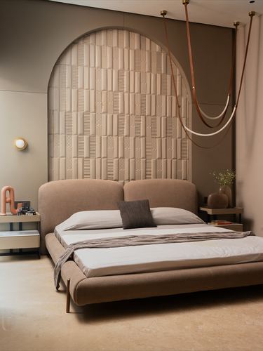 Bedroom with arched textured wall panel behind upholstered bed and looping pendant lights
