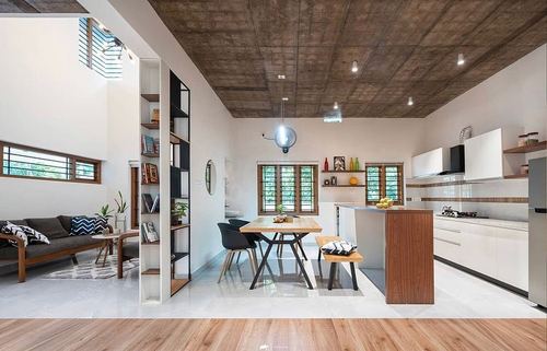 Open-plan living, dining and kitchen space with exposed concrete ceiling and central shelving divider