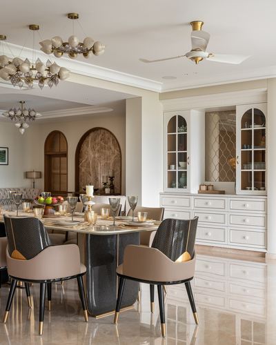 Formal dining room with sculptural chandeliers, marble table, black and beige chairs, arched niche cabinetry