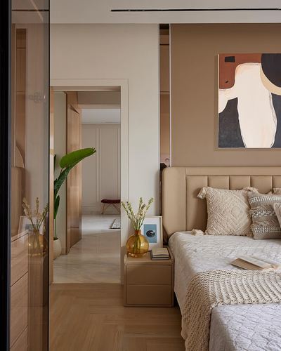 Beige bedroom with channel-tufted headboard, abstract art, and view through mirrored doors to hallway