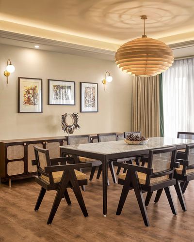 Dining room with marble table, cane-backed chairs, and large wooden pendant light