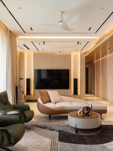 Living room with curved beige sofa, backlit TV wall, and green leather recliner
