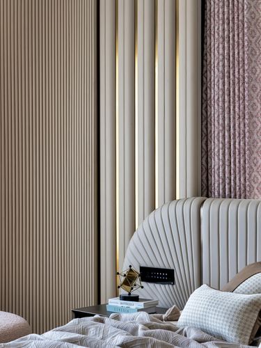 Detail of fluted beige wall panelling with brass lighting strips beside a scalloped headboard and patterned curtain.