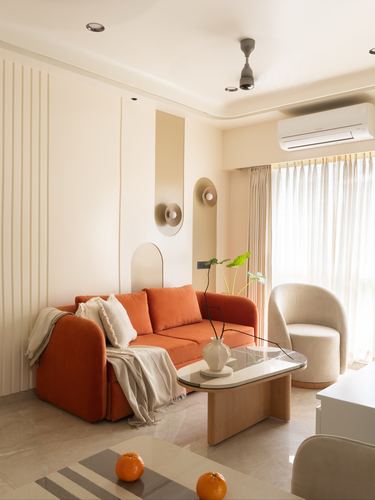 Terracotta sofa with cream armchair and curved wood coffee table in minimalist living room
