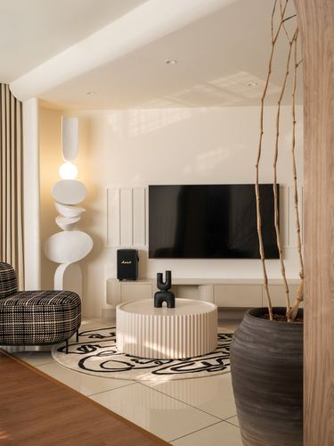 Living room with fluted round coffee table, sculptural white floor lamp, and wall-mounted tv on paneled wall