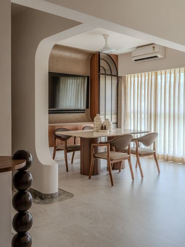 Curved archway opens into a dining nook with marble table, wood chairs, and arched mirror wall panel